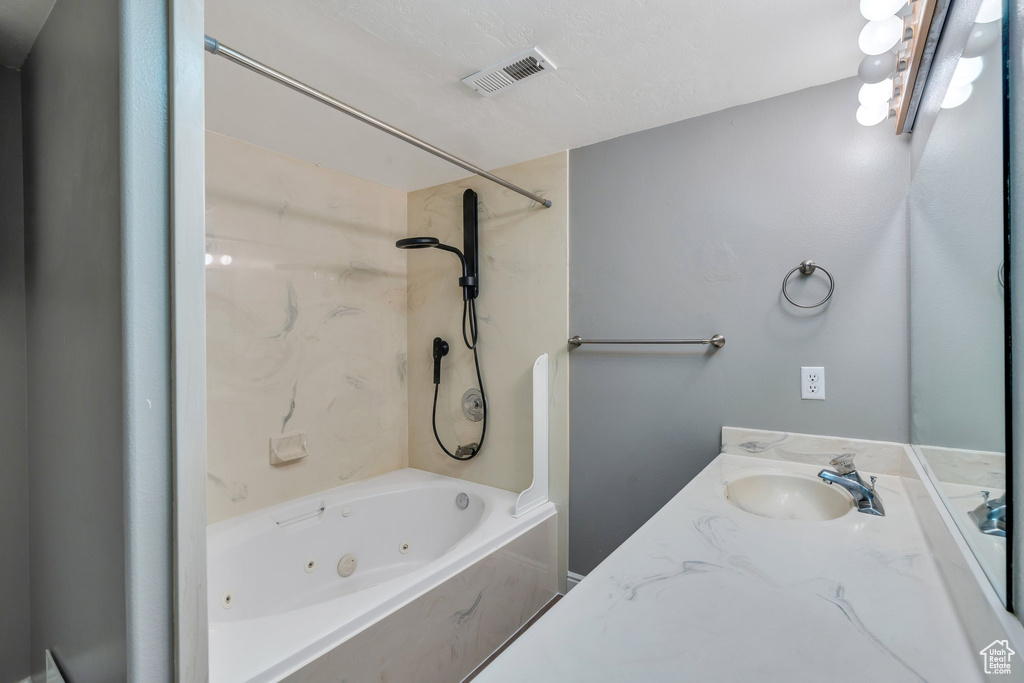 Bathroom featuring a combined bath / shower with jetted tub and vanity