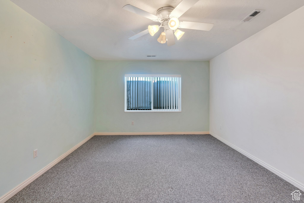 Carpeted spare room with ceiling fan and baseboards