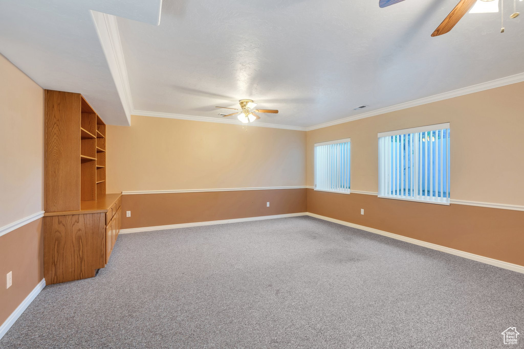 Spare room with a ceiling fan, crown molding, and light carpet