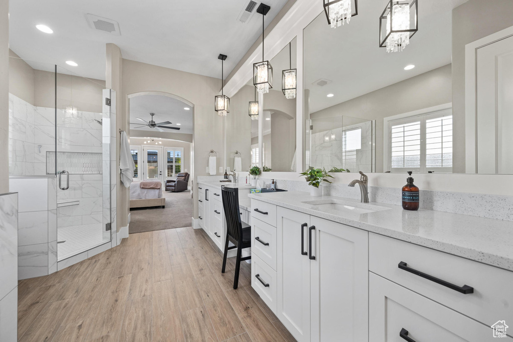 Bathroom with a ceiling fan, a shower stall, vanity, wood finished floors, and recessed lighting