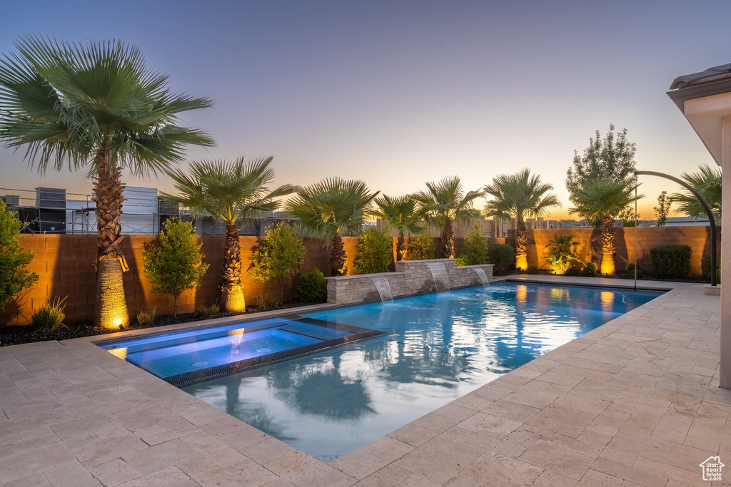 View of swimming pool with a fenced backyard, a pool with connected hot tub, and a patio