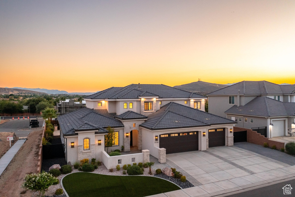 View of front facade featuring an attached garage, concrete driveway, stone siding, stucco siding, and a tile roof