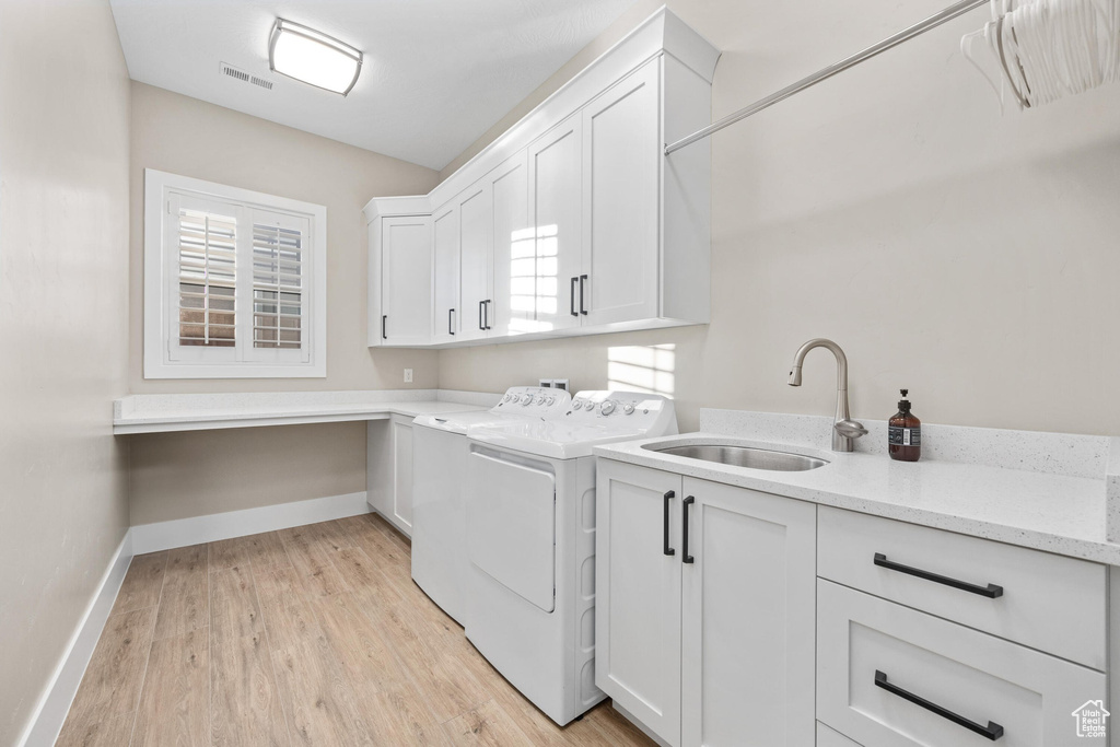 Washroom with cabinet space, washing machine and dryer, and light wood-type flooring