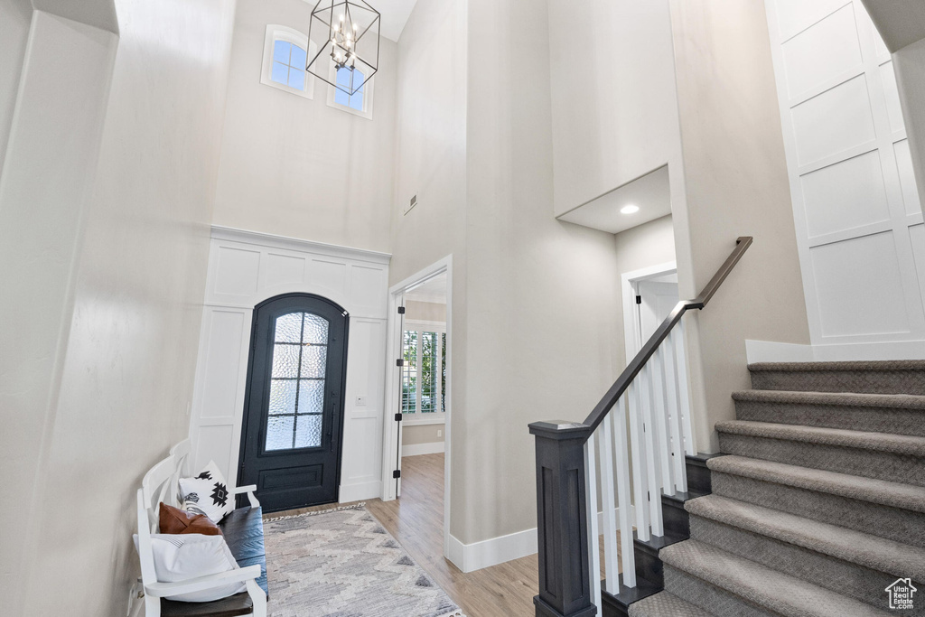 Entryway with a high ceiling, light wood-style floors, stairway, and a chandelier