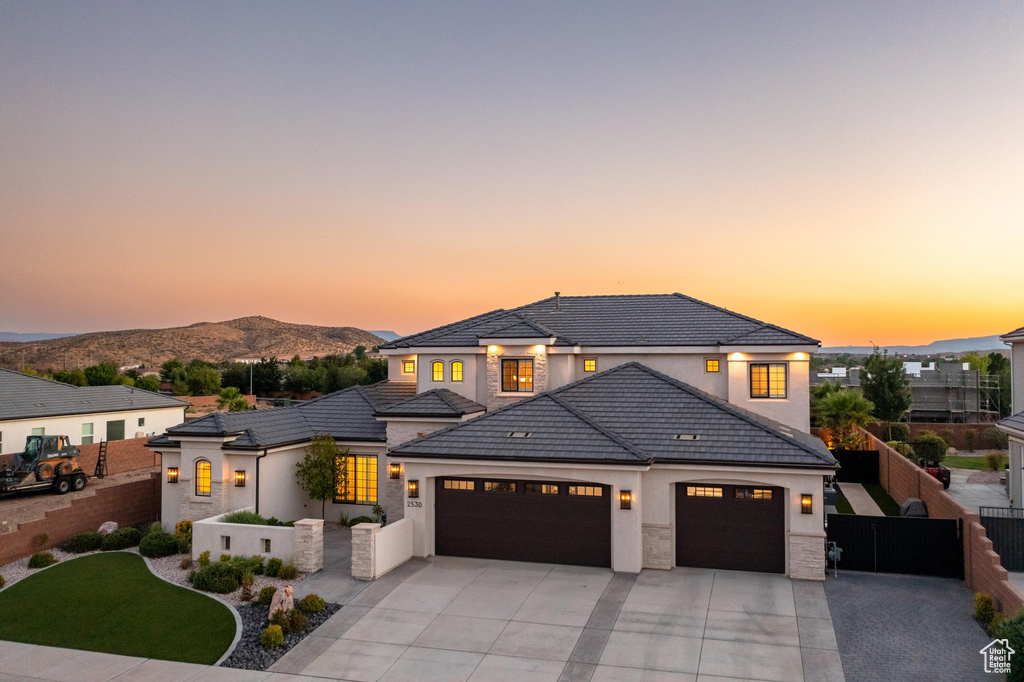 View of front facade featuring a garage, driveway, a mountain view, stucco siding, and a tile roof