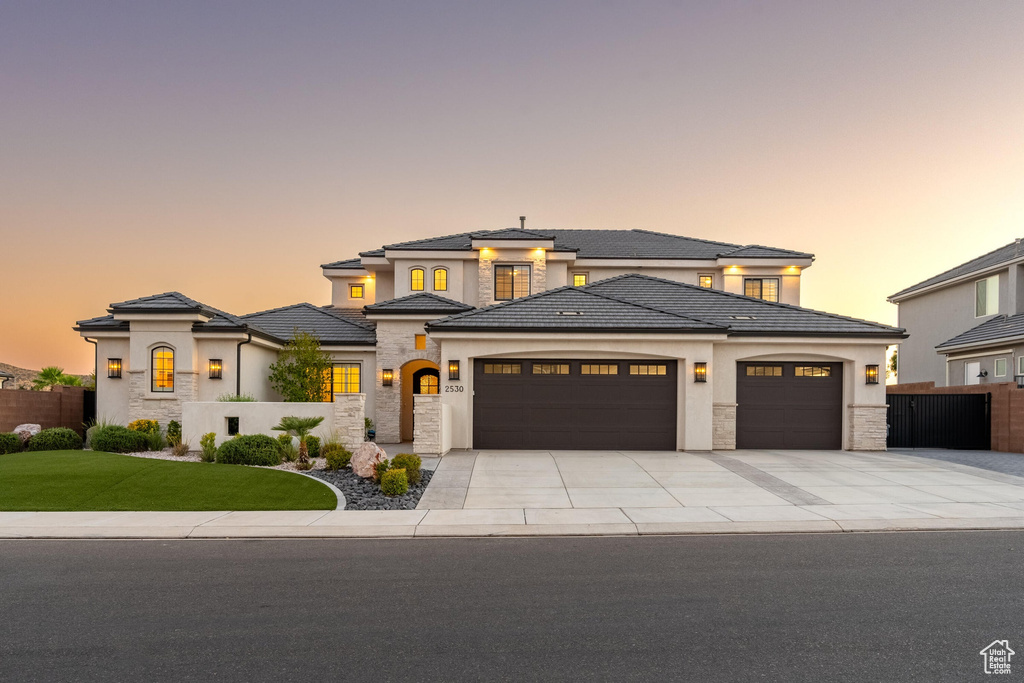 Prairie-style house featuring stone siding, a garage, concrete driveway, and stucco siding