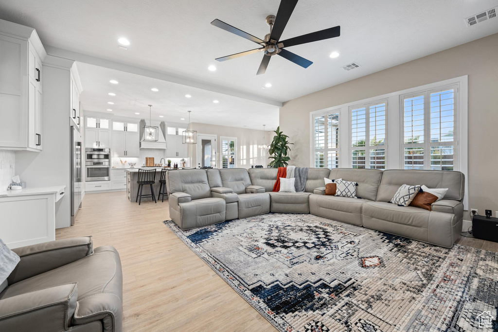 Living area with ceiling fan, light wood-style flooring, and recessed lighting