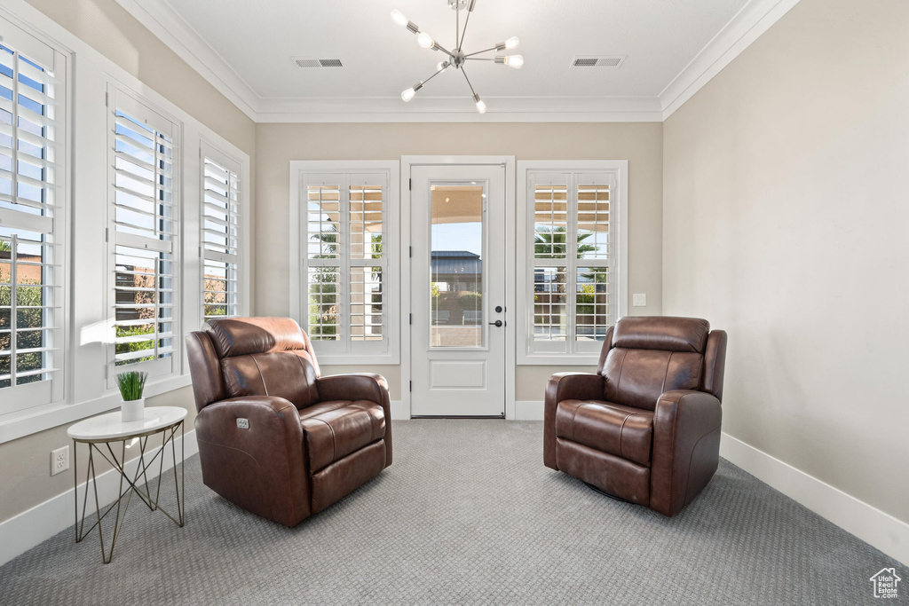 Sitting room featuring a chandelier, crown molding, and carpet flooring