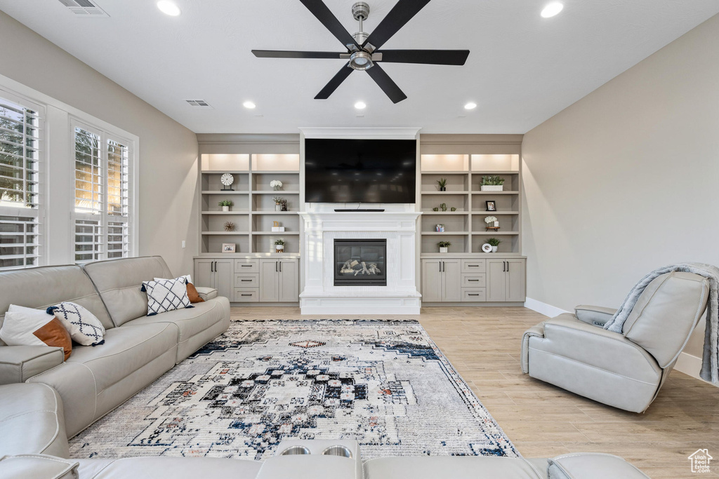 Living area featuring a ceiling fan, a glass covered fireplace, recessed lighting, and light wood-type flooring