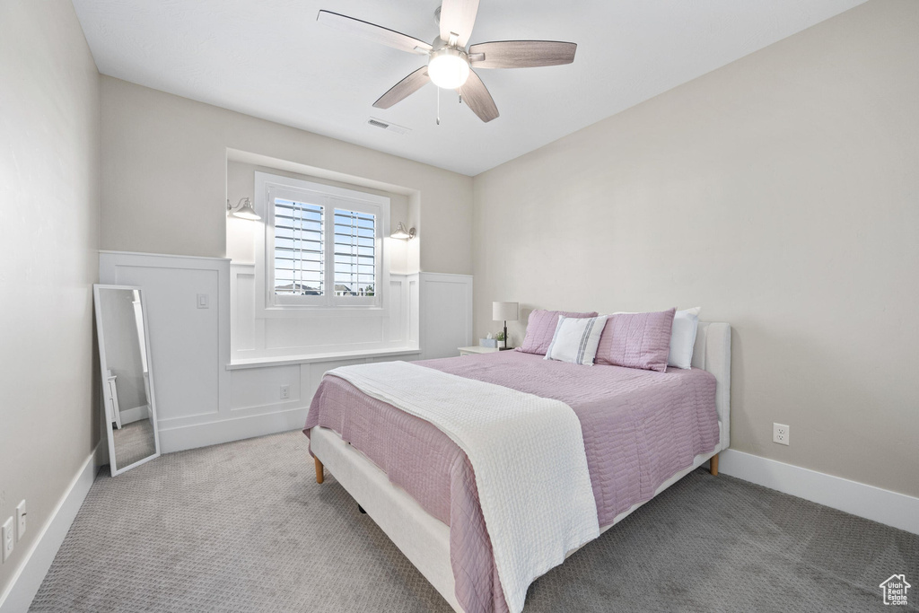 Carpeted bedroom with a ceiling fan and baseboards