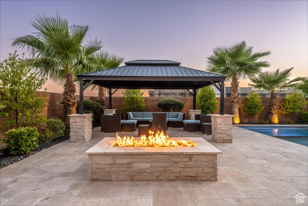 Patio terrace at dusk with a gazebo, an outdoor living space with a fire pit, a patio, and a fenced backyard
