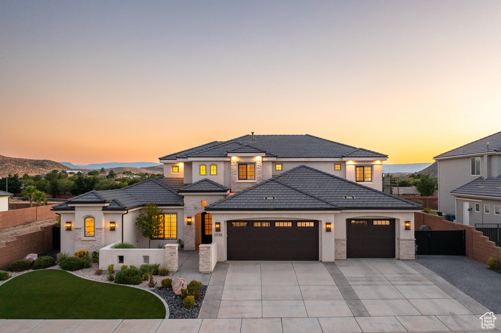 View of front of house with a garage, driveway, stucco siding, stone siding, and a tiled roof