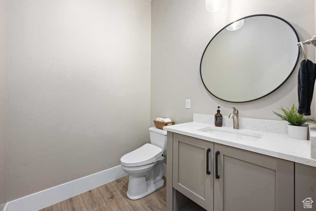 Half bath featuring wood finished floors and vanity