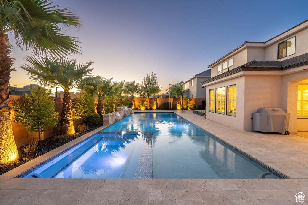 View of pool featuring a pool with connected hot tub, a patio area, a fenced backyard, and a grill