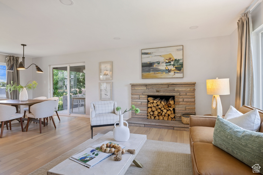 Living area featuring healthy amount of natural light, light wood-type flooring, and a stone fireplace