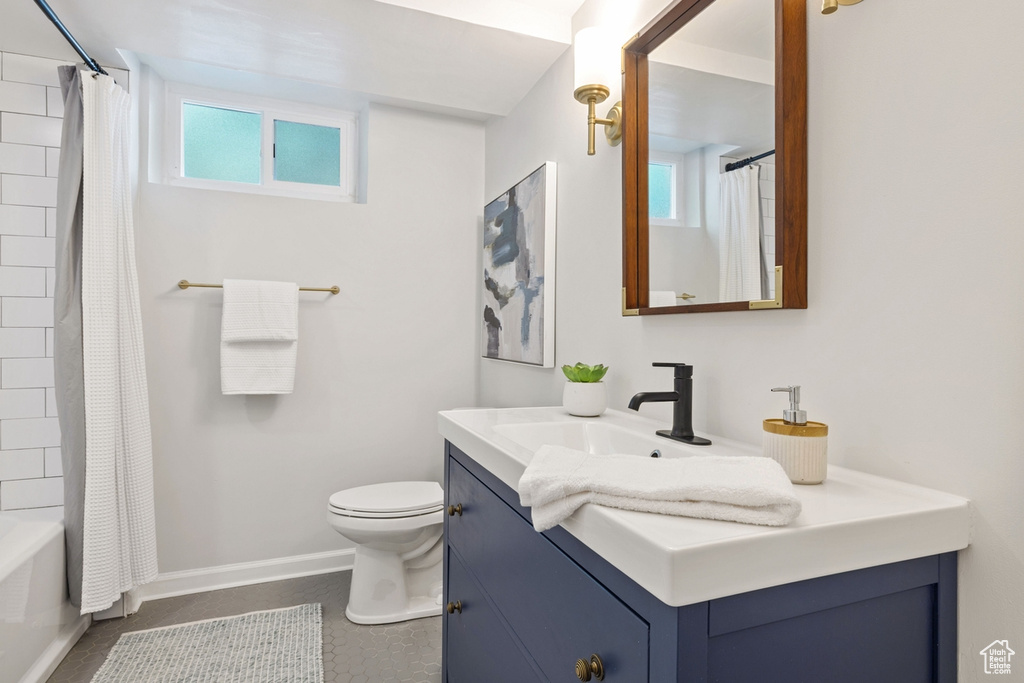 Bathroom with vanity, shower / tub combo, and tile patterned flooring