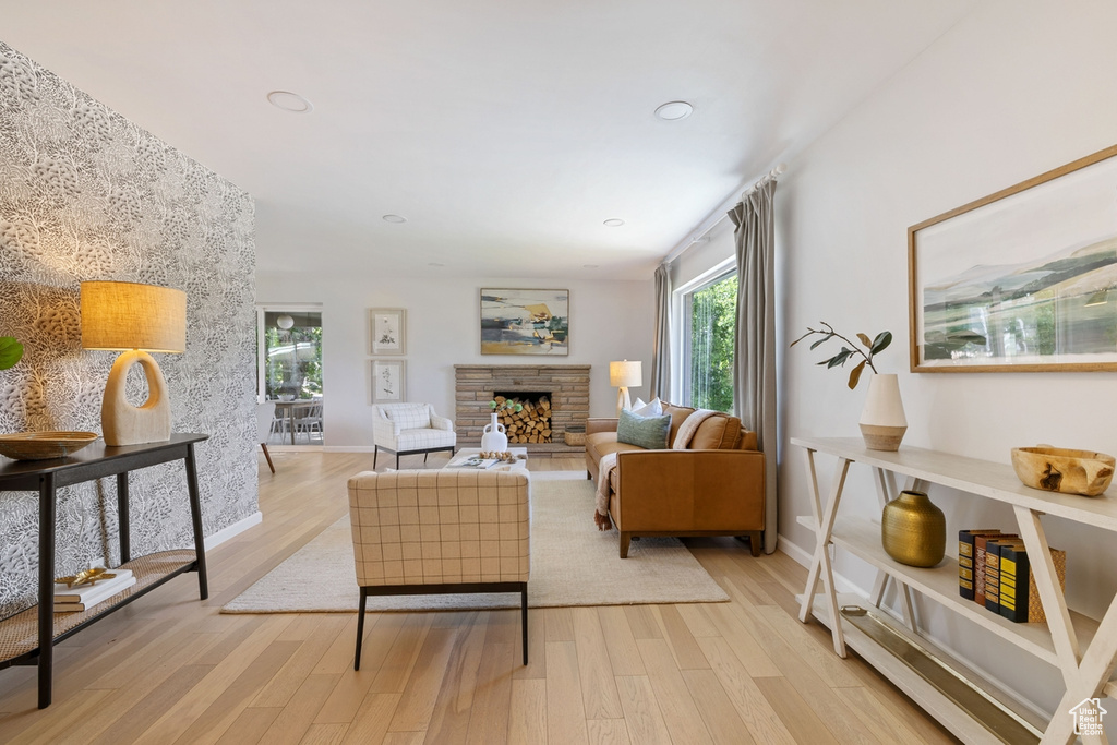 Living area with light wood finished floors, a stone fireplace, and recessed lighting