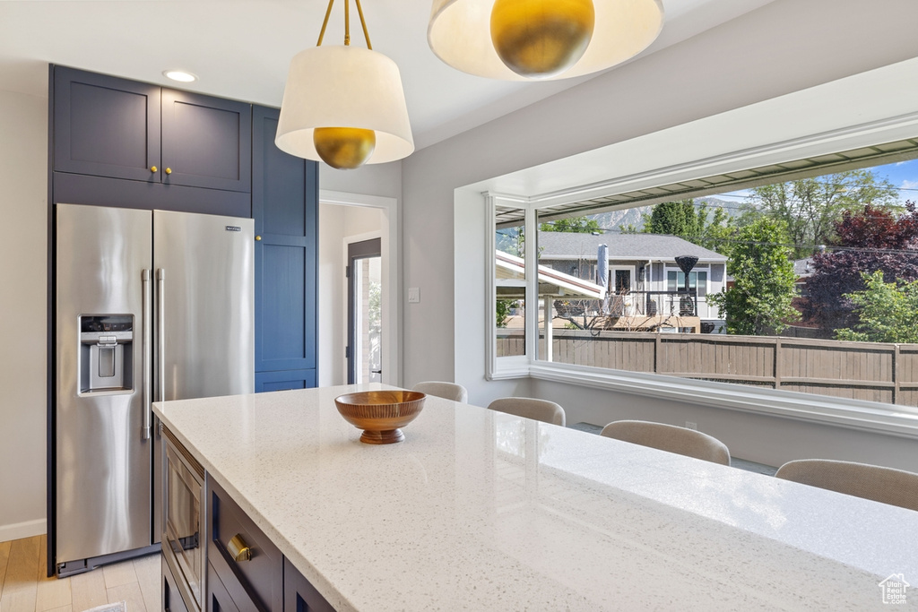Kitchen with appliances with stainless steel finishes, light stone countertops, plenty of natural light, decorative light fixtures, and recessed lighting