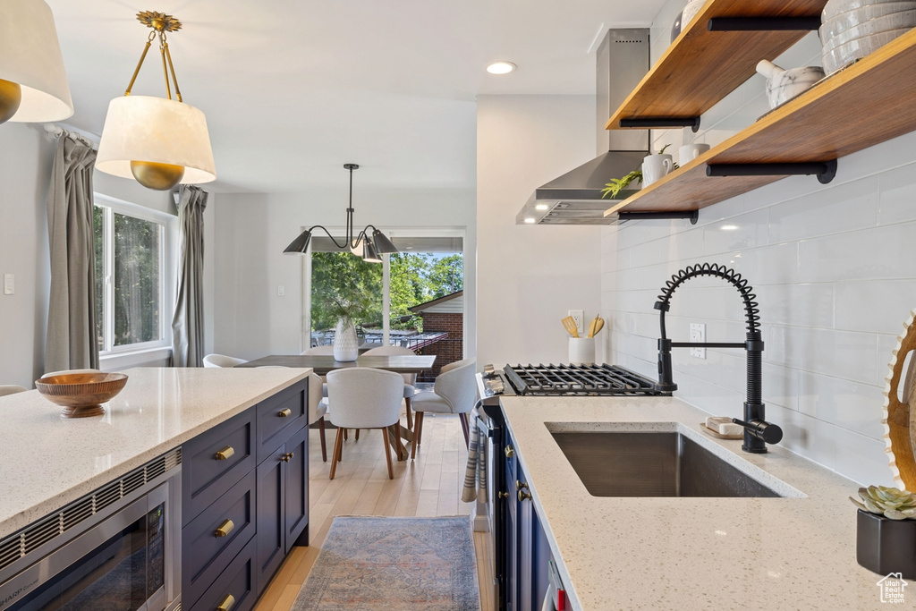 Kitchen featuring open shelves, stainless steel microwave, blue cabinets, backsplash, and recessed lighting
