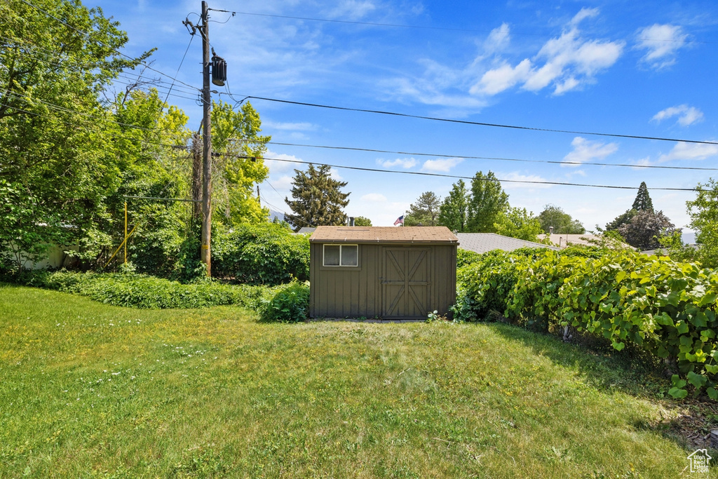 View of grassy yard with a storage shed