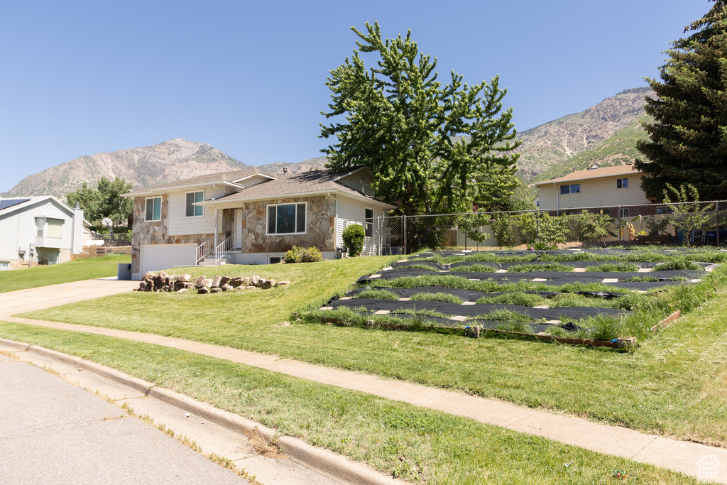 Split level home with stone siding, a mountain view, driveway, and an attached garage