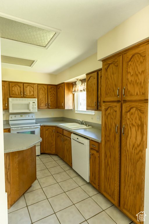 Kitchen featuring white appliances, brown cabinets, light countertops, and light tile patterned floors
