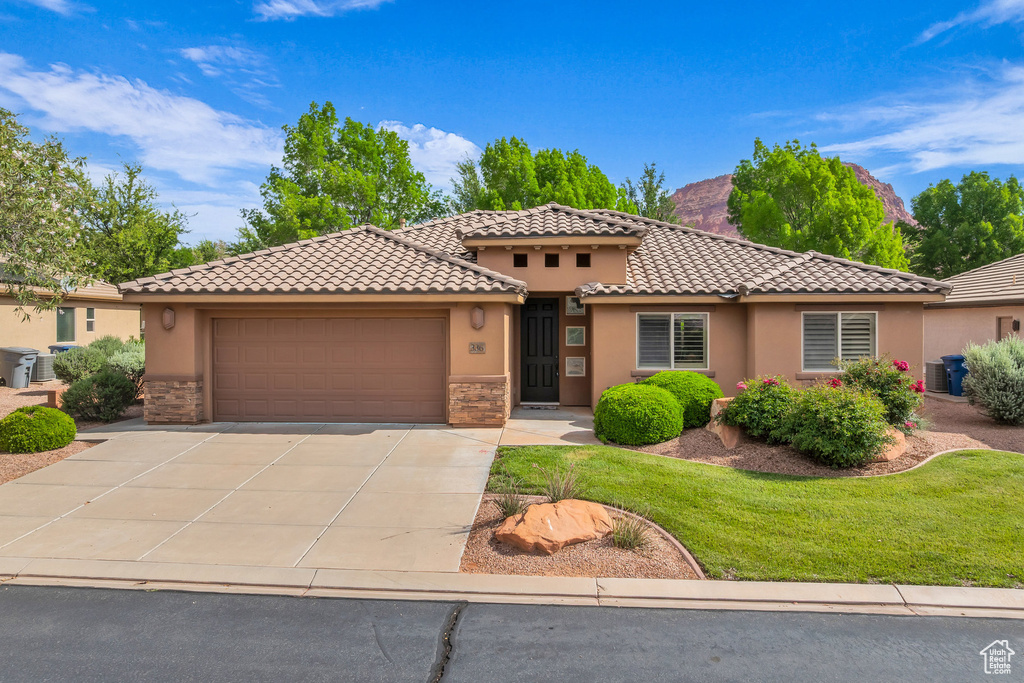 Mediterranean / spanish-style home featuring stucco siding, stone siding, an attached garage, concrete driveway, and a tile roof