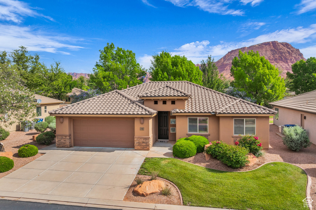 Mediterranean / spanish house with a mountain view, stucco siding, a garage, and concrete driveway