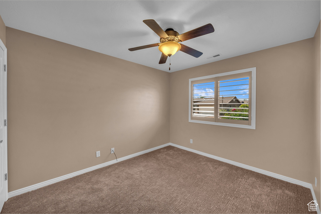 Spare room featuring carpet flooring and a ceiling fan