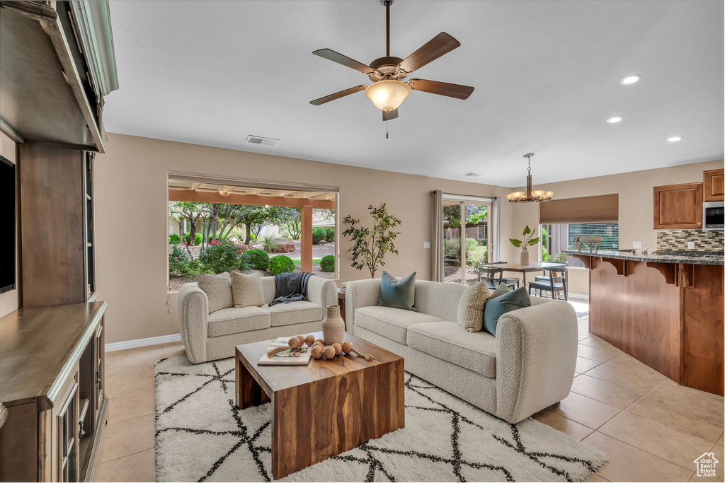 Living area featuring a ceiling fan, light tile patterned flooring, recessed lighting, and a chandelier