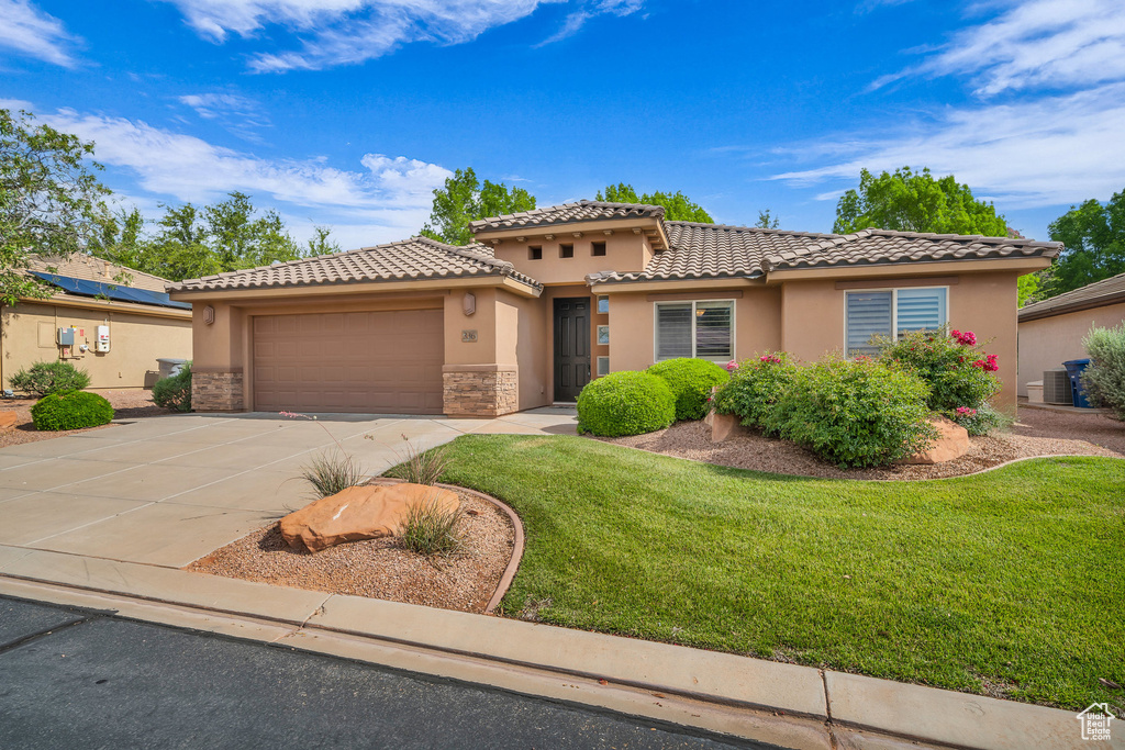 Mediterranean / spanish house with stucco siding, an attached garage, a tile roof, and concrete driveway