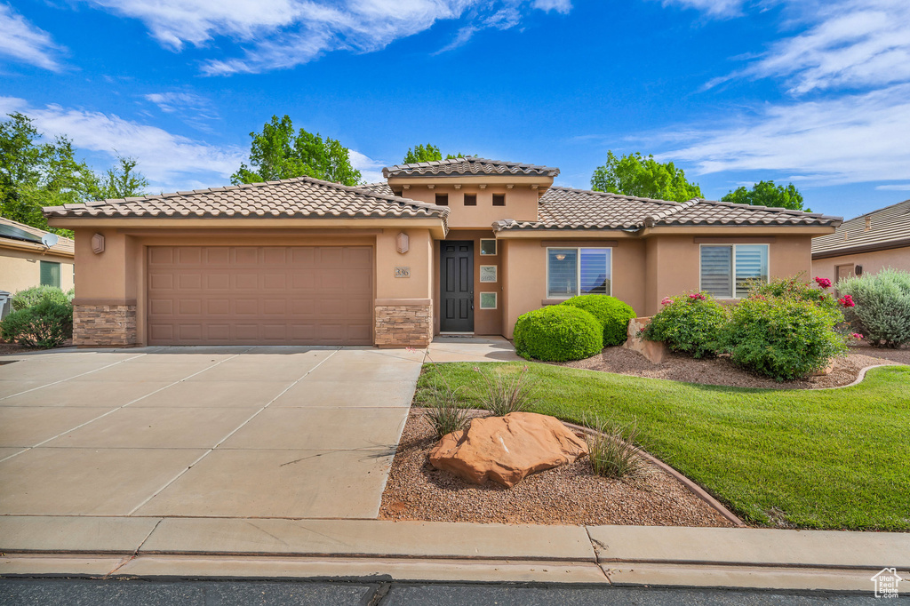 View of front of house featuring stucco siding, a tile roof, stone siding, concrete driveway, and an attached garage
