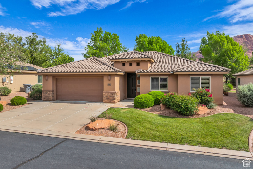 Mediterranean / spanish house with a garage, stucco siding, concrete driveway, and a tiled roof