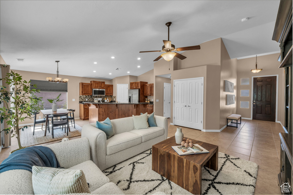 Living room with a chandelier, ceiling fan, light tile patterned floors, recessed lighting, and high vaulted ceiling