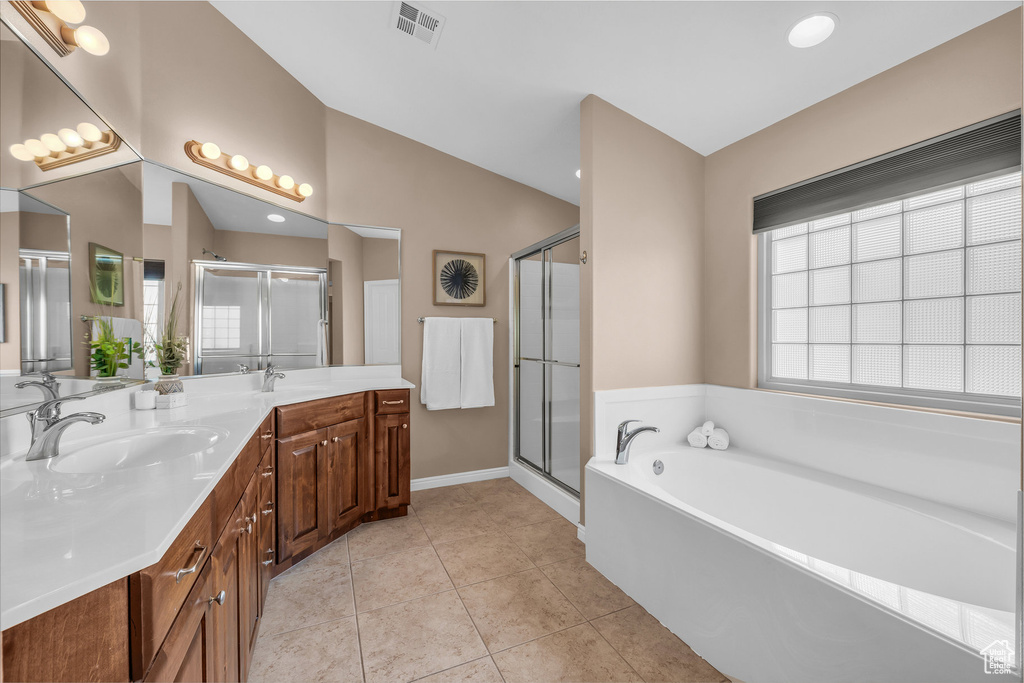 Full bath with a garden tub, double vanity, a shower stall, vaulted ceiling, and tile patterned floors
