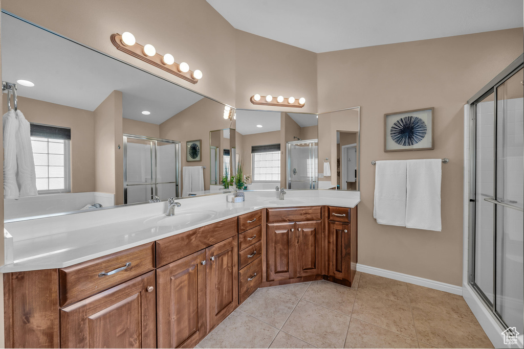 Bathroom with double vanity, a shower stall, and tile patterned flooring