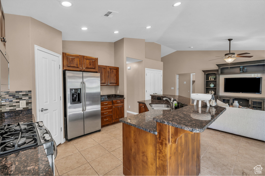 Kitchen featuring stainless steel appliances, vaulted ceiling, ceiling fan, brown cabinets, and open floor plan