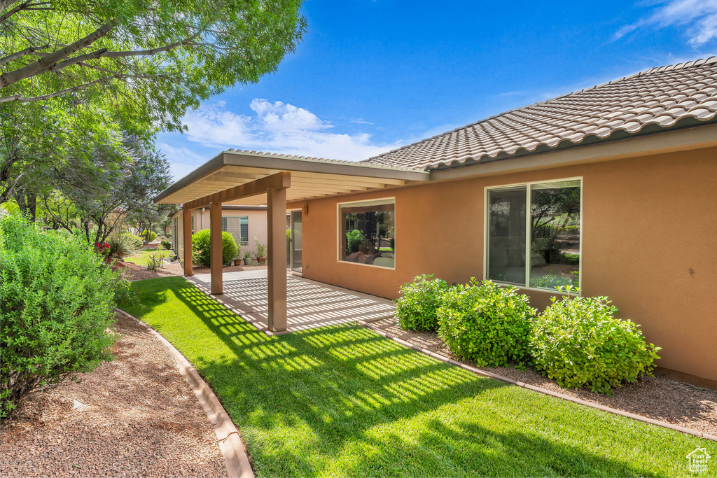 Rear view of house with stucco siding, a yard, a patio area, and a tiled roof
