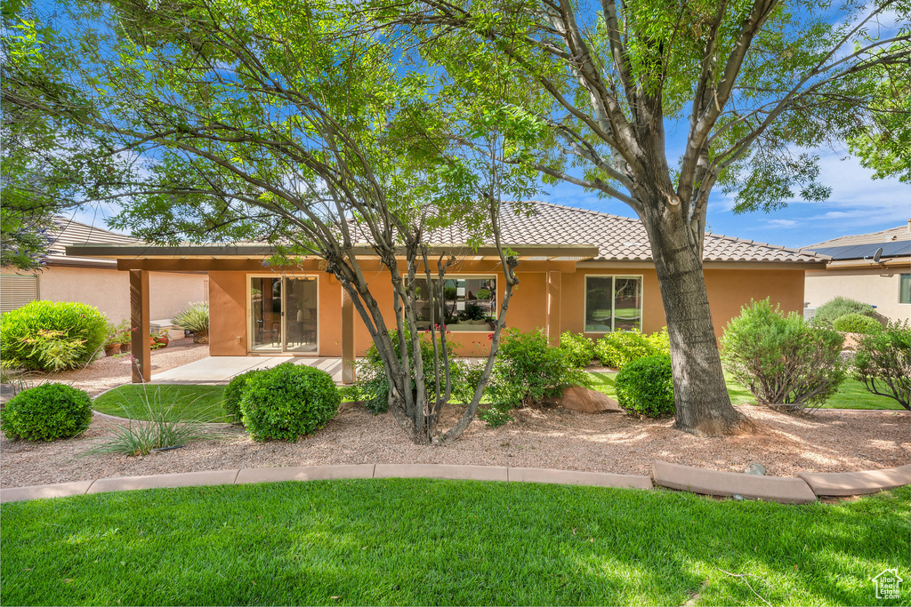 View of front of house featuring stucco siding, a tiled roof, a front yard, and a patio area