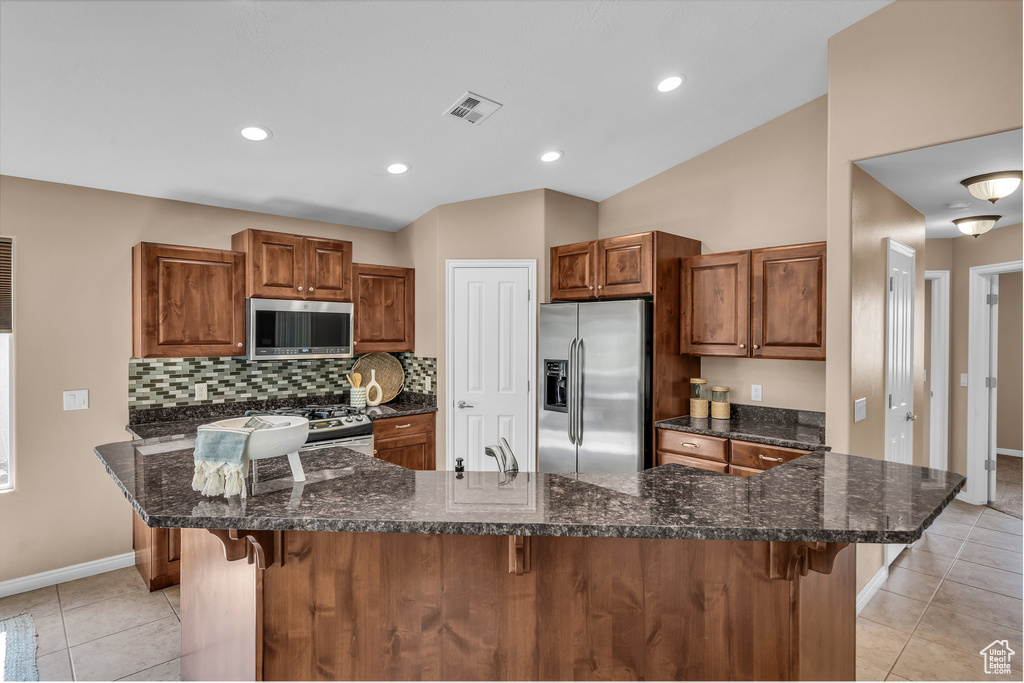 Kitchen with stainless steel appliances, light tile patterned floors, a kitchen bar, tasteful backsplash, and recessed lighting