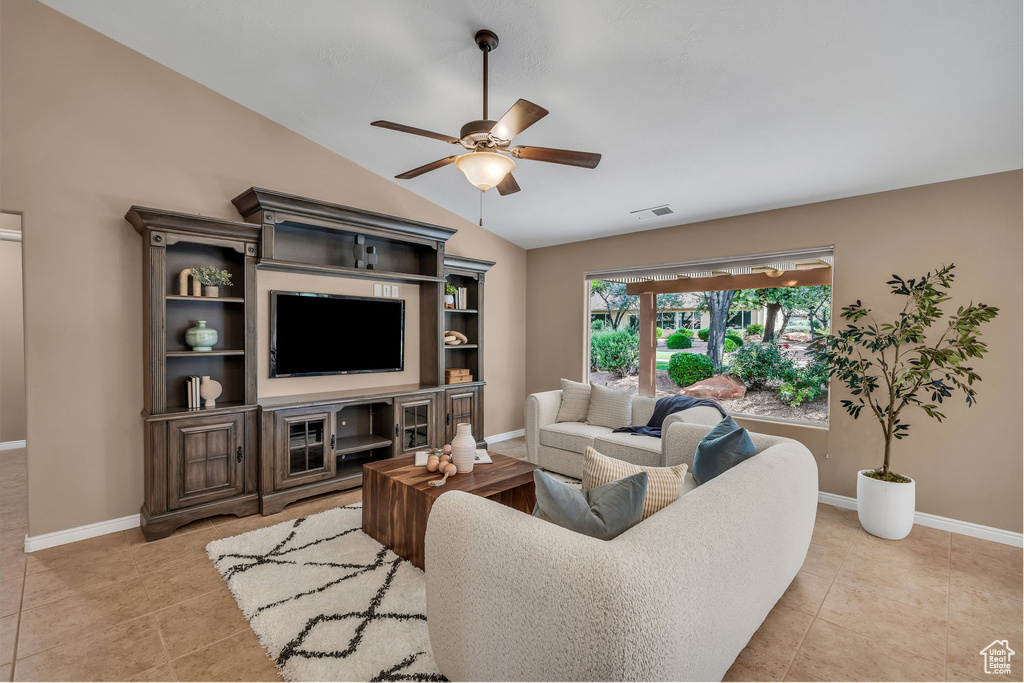 Living room with a ceiling fan, lofted ceiling, and light tile patterned flooring