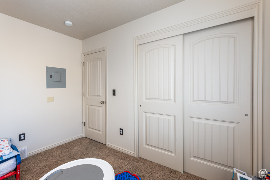 Unfurnished bedroom featuring electric panel, carpet flooring, a closet, and baseboards