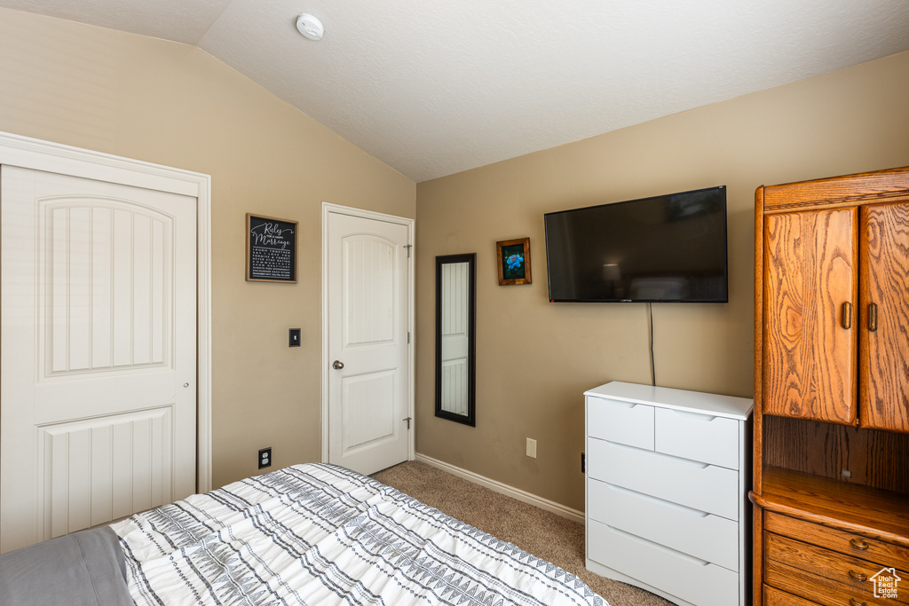Bedroom featuring vaulted ceiling, light colored carpet, and baseboards
