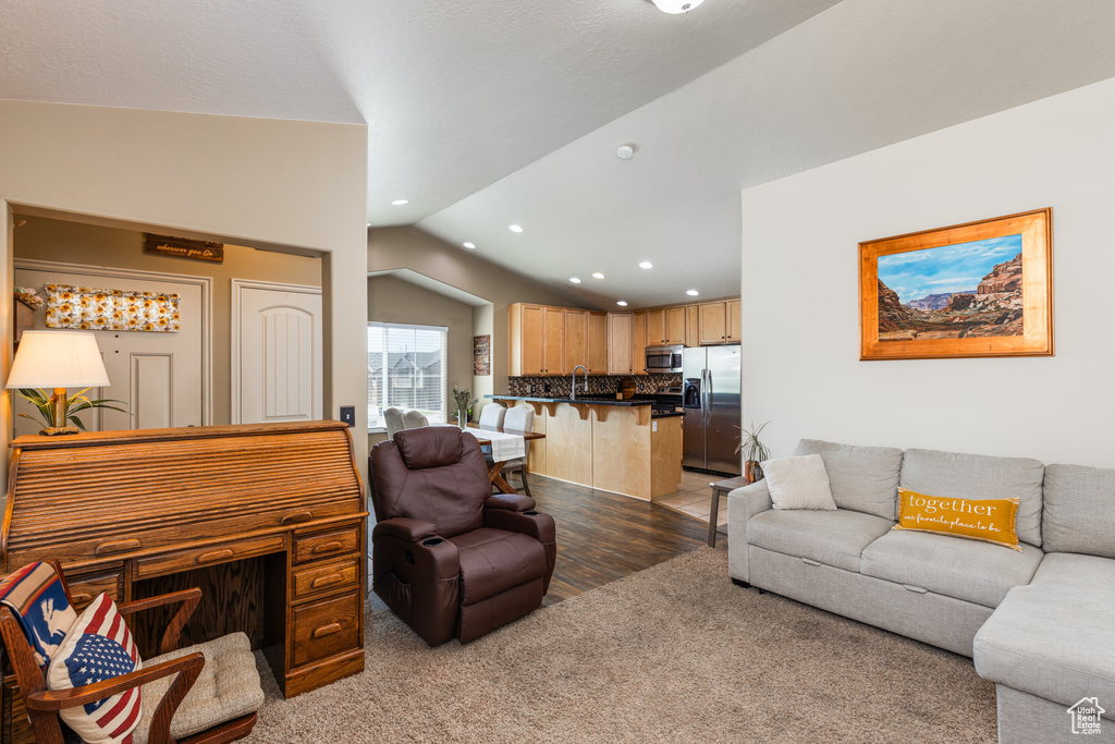 Living area featuring lofted ceiling, recessed lighting, light wood-style flooring, and light carpet