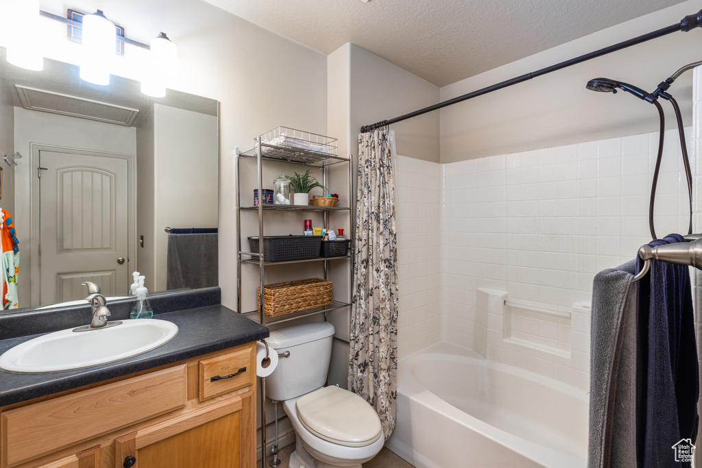Full bath with shower / tub combo with curtain, vanity, toilet, and a textured ceiling