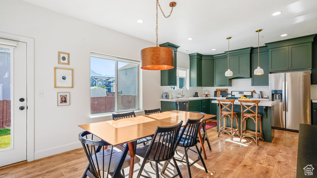 Dining room with light wood finished floors and recessed lighting