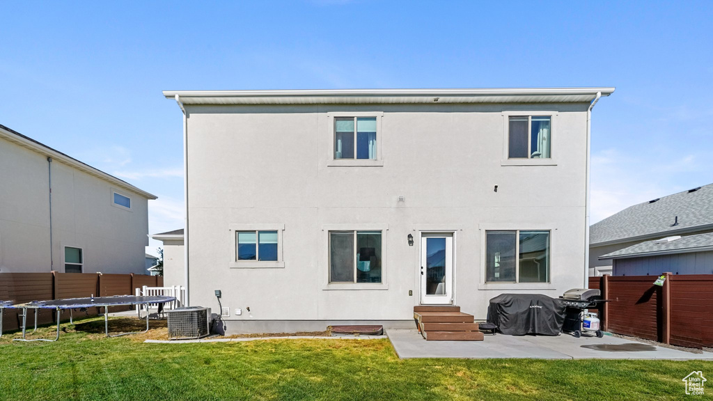 Back of house with entry steps, a trampoline, stucco siding, and a patio