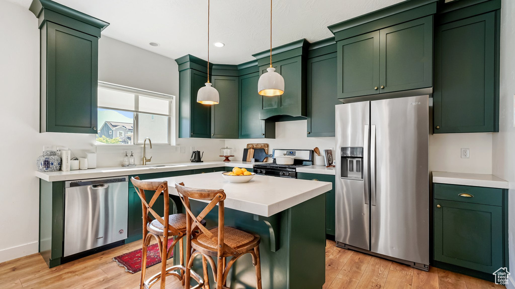 Kitchen featuring stainless steel appliances, green cabinets, light wood-style flooring, light countertops, and recessed lighting