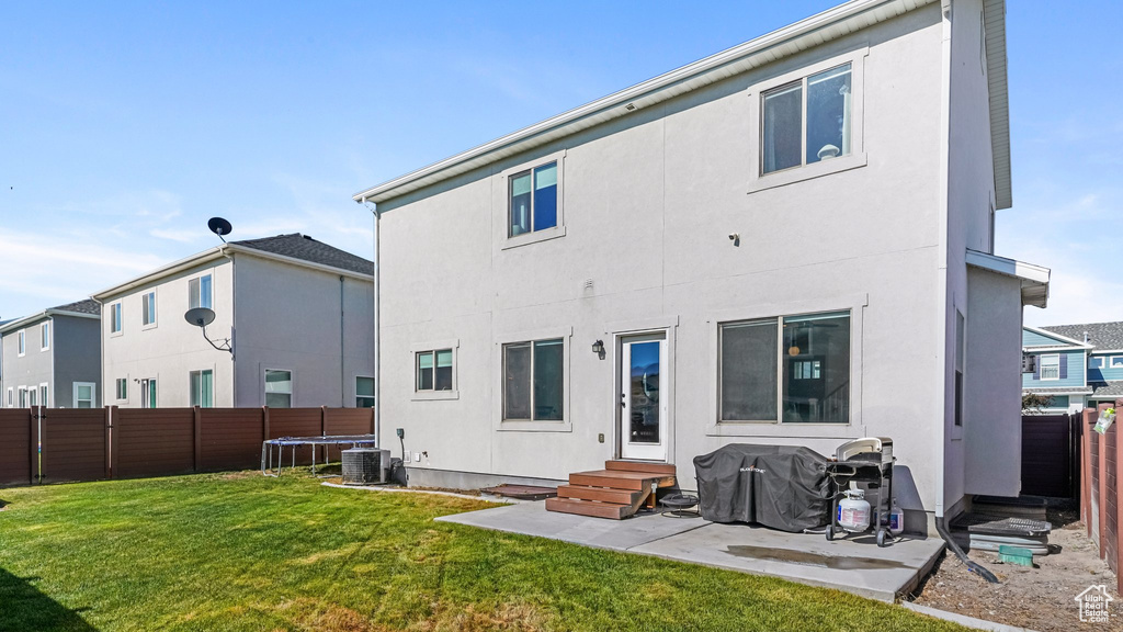 Rear view of house with entry steps, a fenced backyard, stucco siding, and a patio