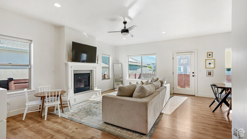 Living area with ceiling fan, wood finished floors, a glass covered fireplace, and recessed lighting